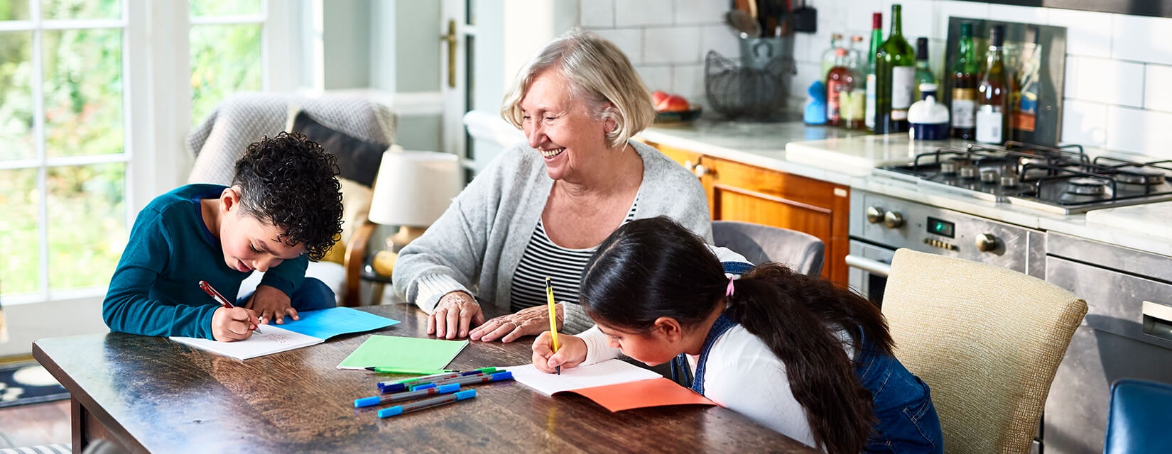 grandmother with two children drawing in kitchen