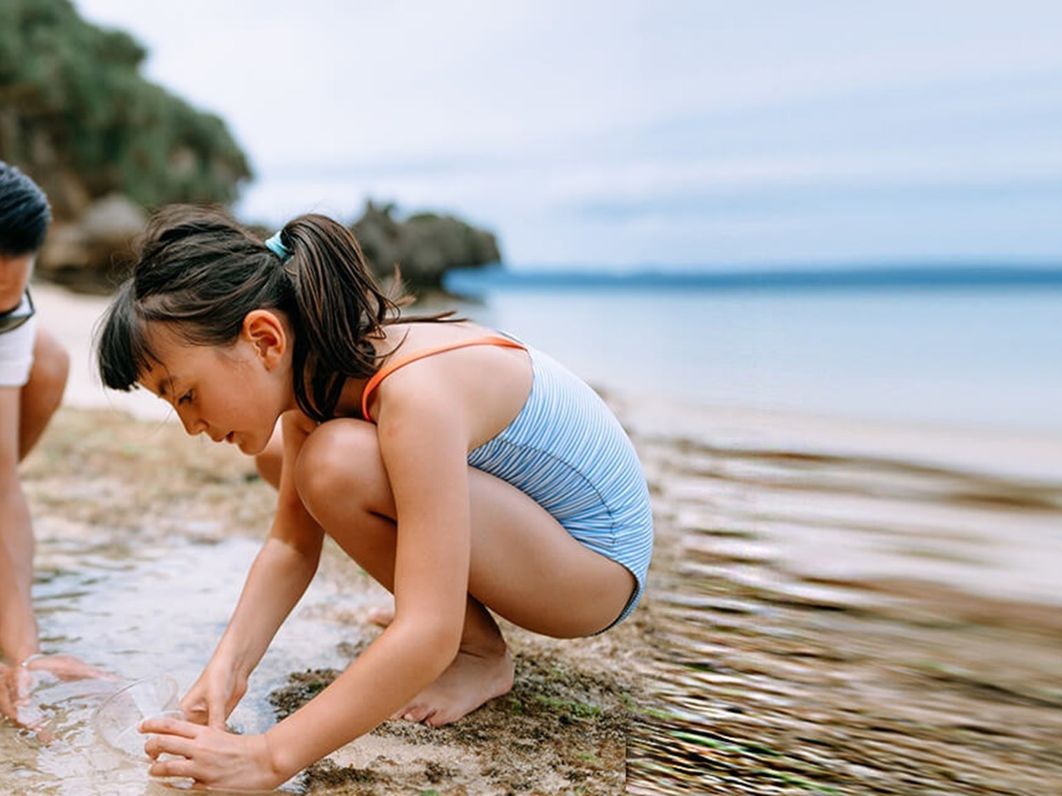 Grandfather, father and girl playing in the sand at the beach