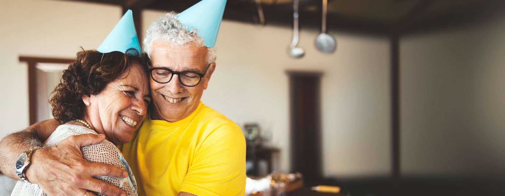 Couple hugging and smiling while wearing party hats