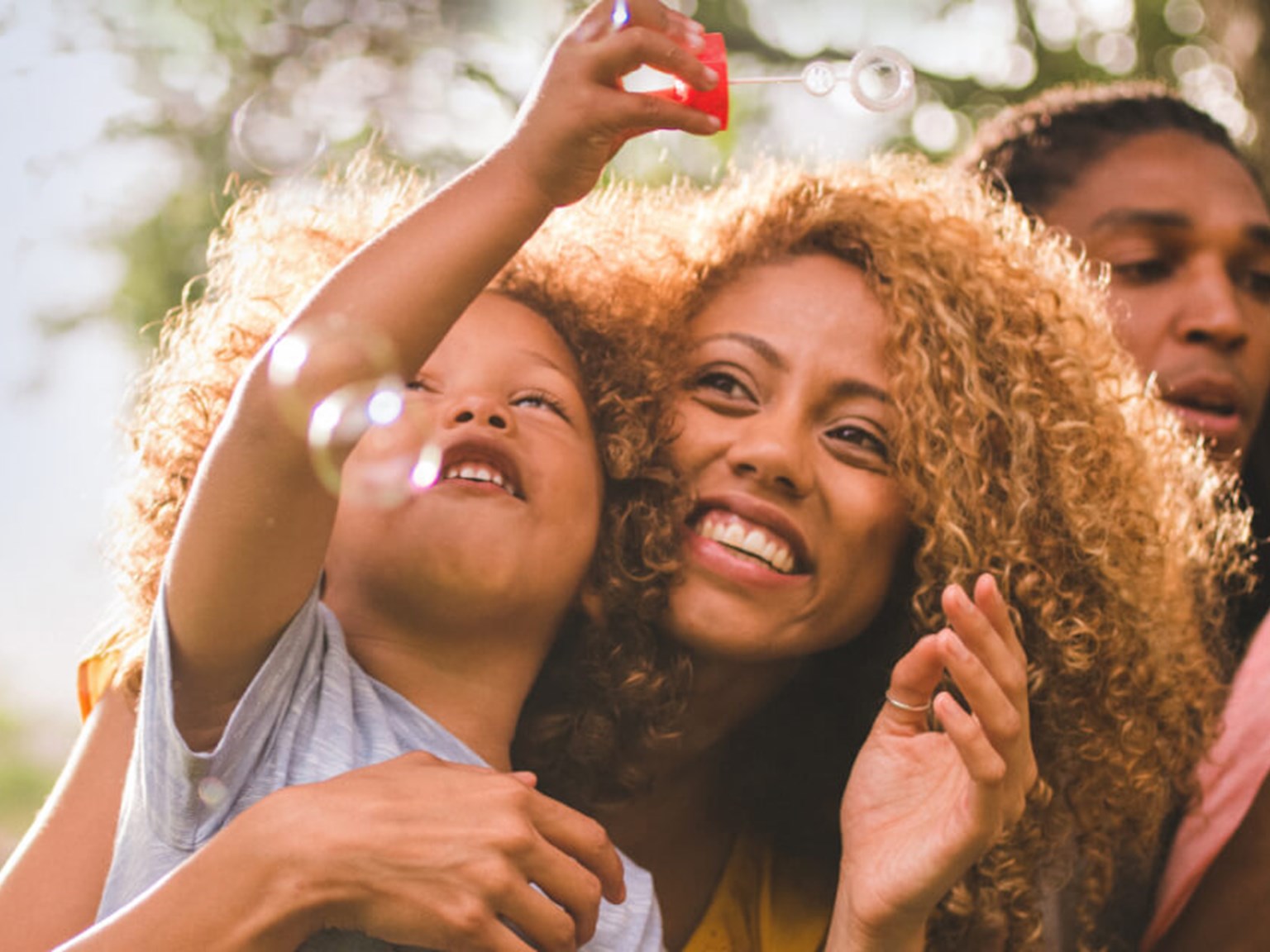 Happy mother, father and two small children blowing bubbles in a field