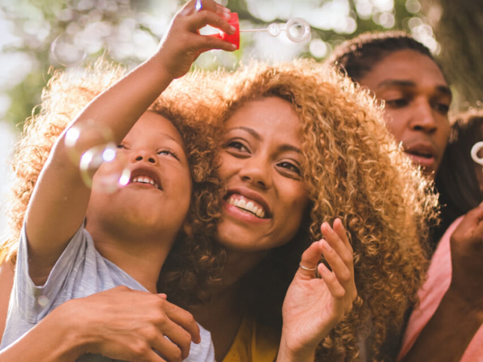 Happy mother, father and two small children blowing bubbles in a field