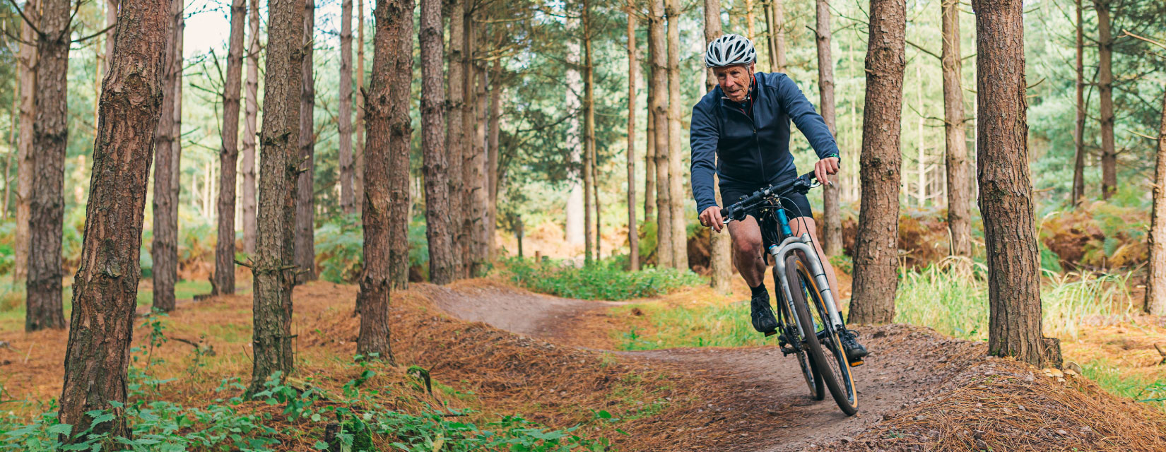 A man in his later years mountain biking through the woods