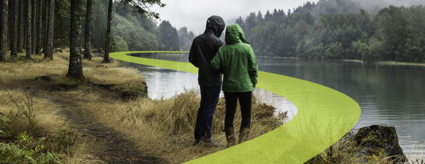 couple stood facing a river on a rainy day. A yellow pathway graphic overlaid curves away into the distance.