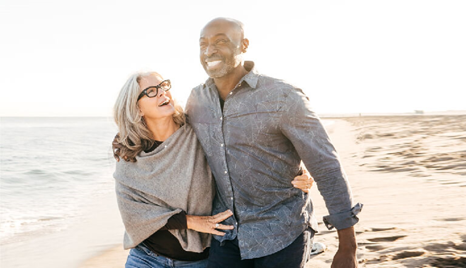 Mature couple walking on the beach arm in arm