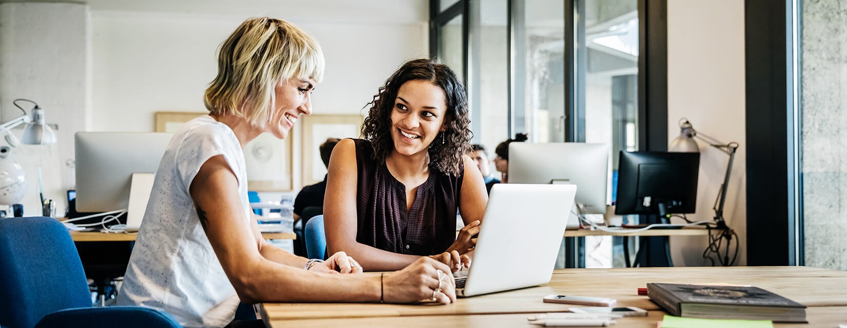 two women looking at laptop in office