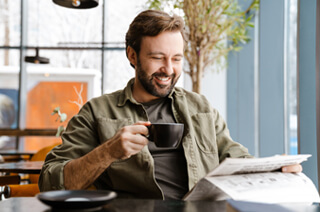Man reading through papers holding a mug