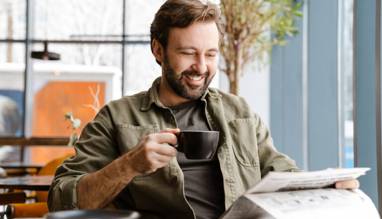 Man reading whilst holding a cup