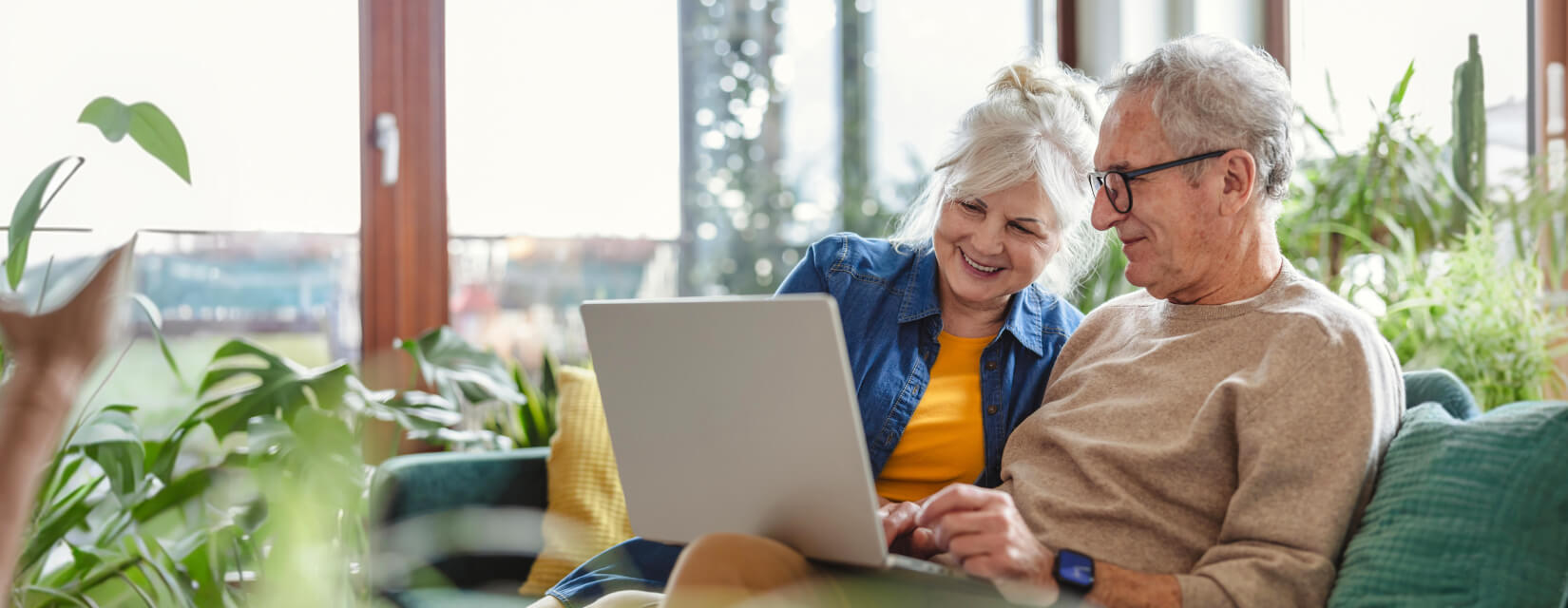 Happy older couple relaxing on a safa with a laptop