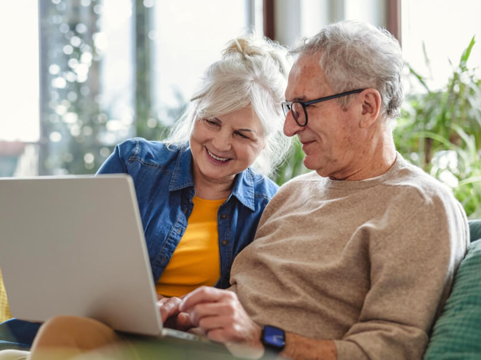 Happy older couple relaxing on a safa with a laptop