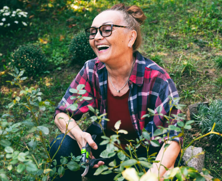 Happy woman prunes plants in her garden