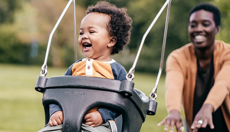mother with baby in the swing at the park
