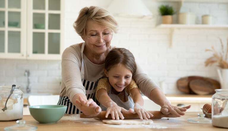 Grandma and granddaughter rolling pastry in the kitchen
