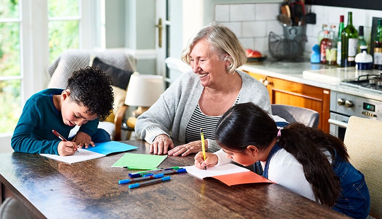 grandmother with two children drawing in kitchen