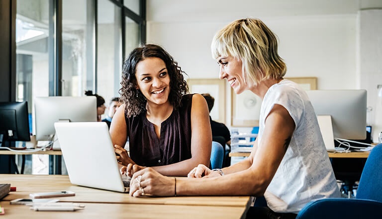 two women working on laptop in office