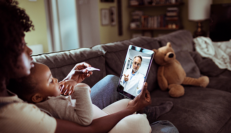 Mother and child looking at a thermometre on the couch