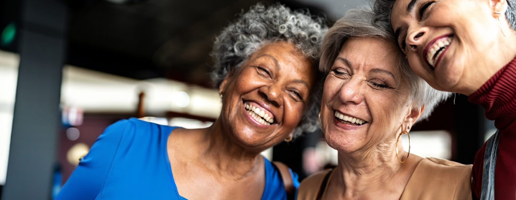 Three women of retirement age smiling and laughing together