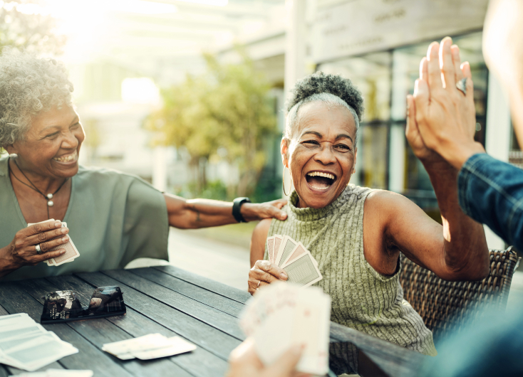 Two ladies of retirement age playing cards and laughing