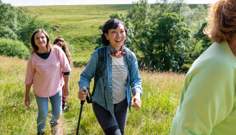 A group of women near retirement age hiking through hills on a sunny day