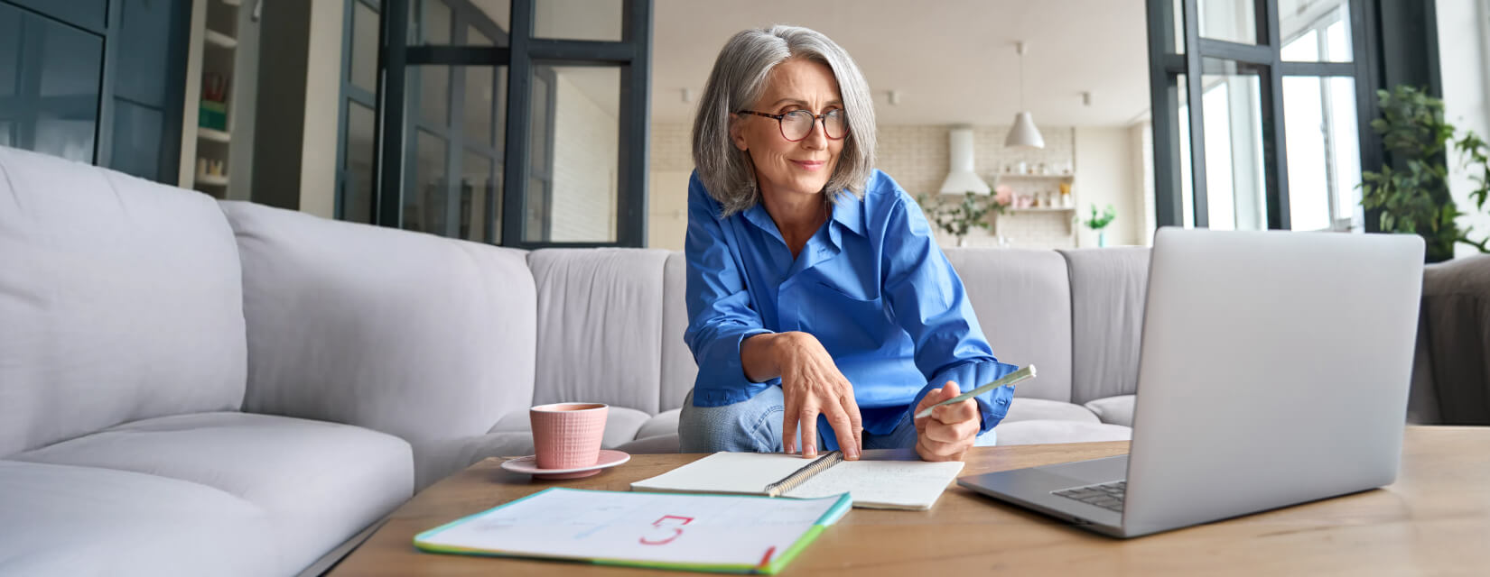 Woman sat on her sofa working on a laptop